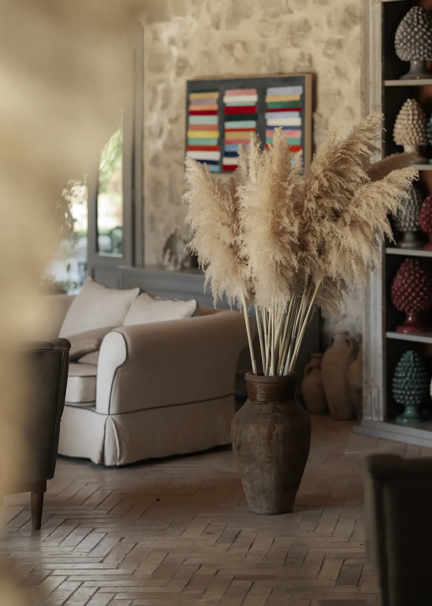 Salon de la masseria aux murs en pierre, avec herbes de la pampa et pommes de pin en céramique sicilienne
