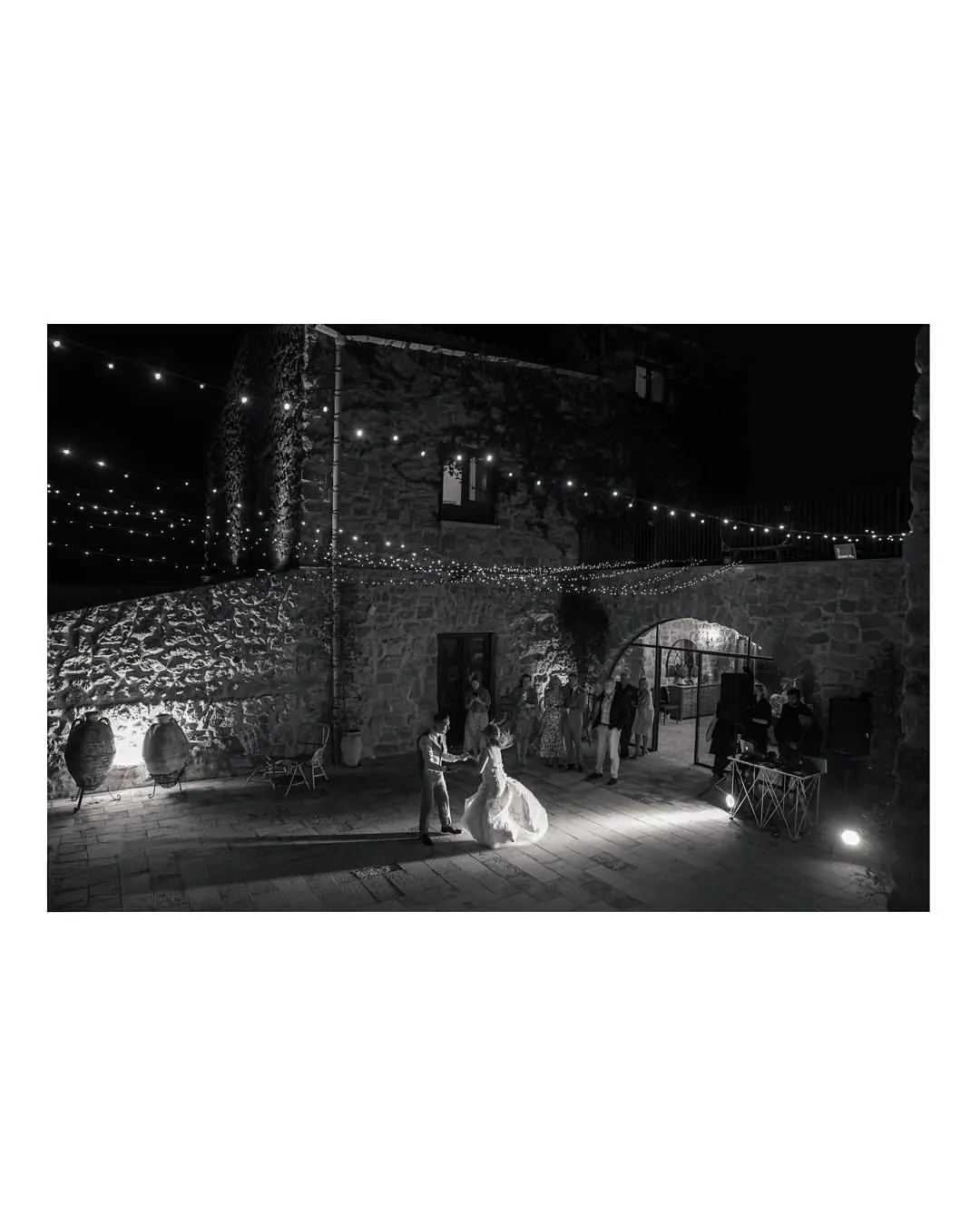 First dance under string lights in the stone courtyard of the wedding venue near Scala dei Turchi
